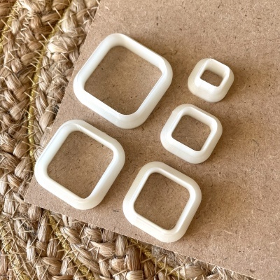 Argolas quadradas de plástico branco sobre cartão e superfície trançada