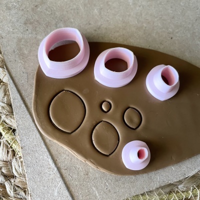 Conjunto de cortadores ovais rosa sobre argila marrom e superfície de cortiça