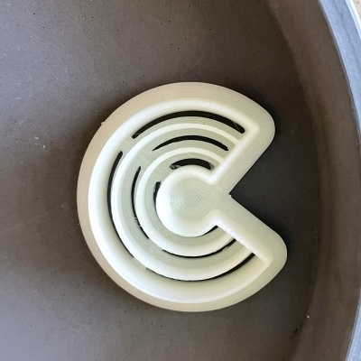 Dispositivo branco de plástico circular com cortes triangulares na superfície cinza