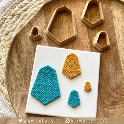 Conjunto de cortadores de massa geométricos e massa colorida texturizada sobre base branca em superfície de madeira