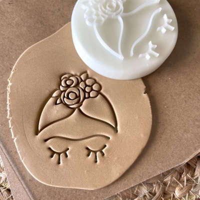 Carimbo branco com desenho floral sobre massa castanha clara em papel pardo