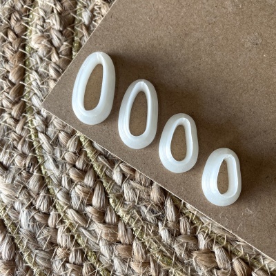 Quatro moldes de silicone brancos de tamanhos variados sobre cartolina e tapete trançado