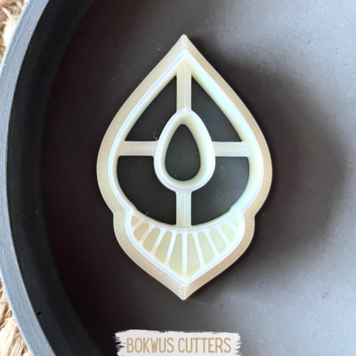 Cortador de biscoitos branco em forma de folha sobre superfície cinza escura com etiqueta 'BOKWUS CUTTERS'.