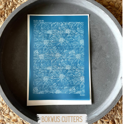 Pôster floral azul e branco dentro de prato cinzento sobre superfície de fibra natural