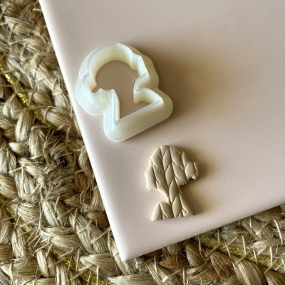 Cookie cutter branco e forma em massa bege sobre superfície rosa e base de palha