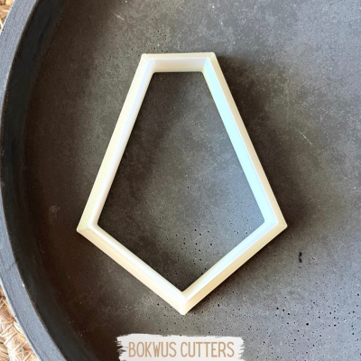 Cortador de massa pentagonal branco sobre tabuleiro escuro com etiqueta BOKWUS CUTTERS