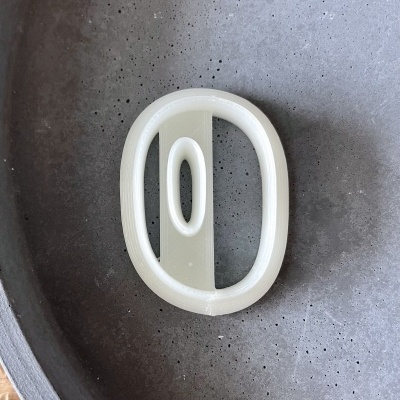 porta-bijuteria oval branco em superfície cinzenta texturada