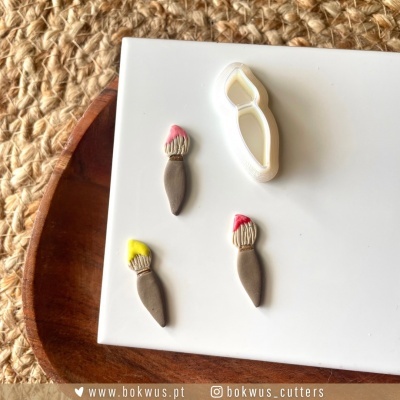 moldes silicone pincéis de pintar com tinta colorida na ponta sobre superfície branca e tabuleiro de madeira