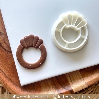 Cortador de massa plastico branco e massa castanha moldada sobre tabuleiro branco e base de madeira