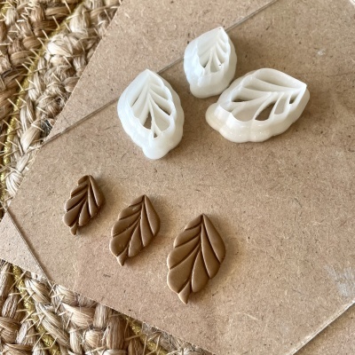 Cortadores de massa brancos em forma de folha com massa marrom modelada em folhas