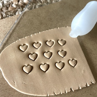 Massa bege com corações em relevo e tubo branco a aplicar líquido