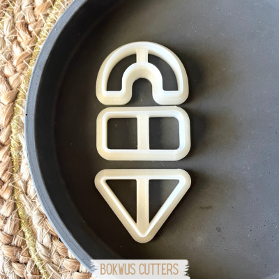 Três cortadores de massa plásticos brancos em prato preto com tapete de palha ao fundo