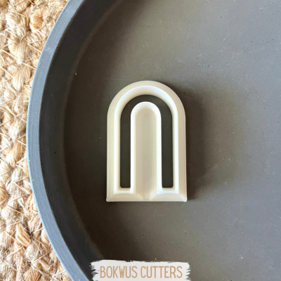 Cortador de biscoitos em forma de arco branco numa bandeja cinza escuro