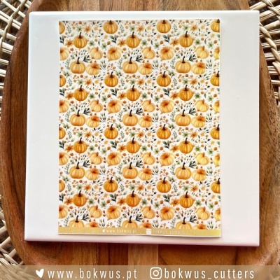 Livro de receitas com capa de abóboras, folhas e bagas em fundo branco sobre prato e mesa de madeira