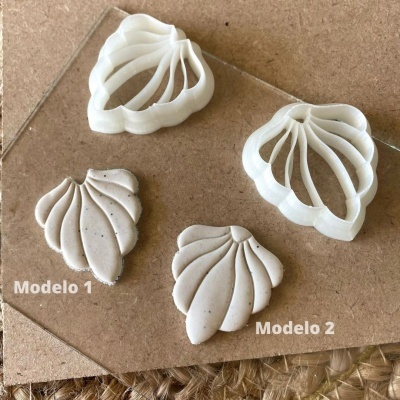 Dois cortadores de massa brancos e respetivos moldes de massa bege claro em formato de concha