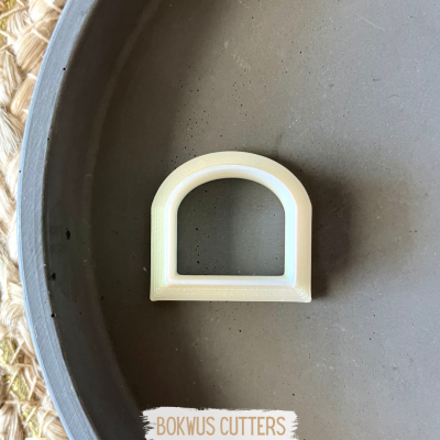 ferramenta de corte branca em forma de arco sobre superfície cinza