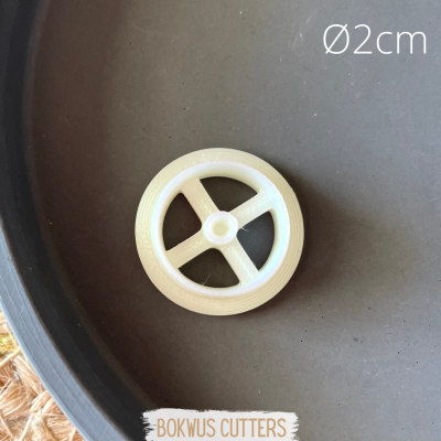 Roda branca de plástico com 2 cm de diâmetro e quatro raios sobre superfície cinzenta.