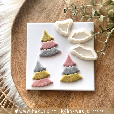 Conjunto de cortadores de massa e camadas coloridas sobre placa branca e base de madeira