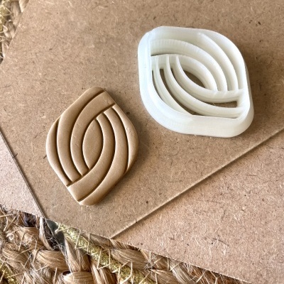 Dois moldes de cortar biscoitos em plástico branco e bege sobre cartão castanho e tapete de fibras naturais