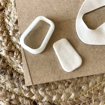 Moldes plásticos brancos sobre cartão castanho e tapete de corda trançada