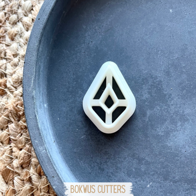 Cortador de massa branco em forma geométrica num prato preto sobre superfície têxtil rústica