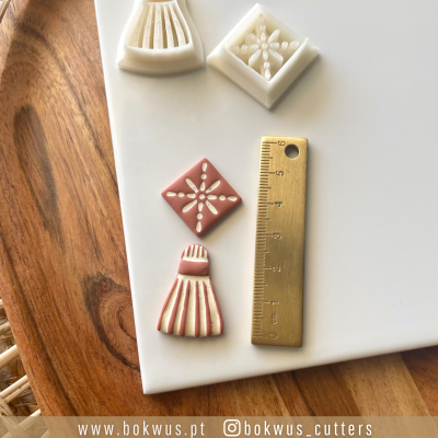 Cortadores de massa em plástico branco com desenhos detalhados e régua metálica dourada sobre superfície de madeira