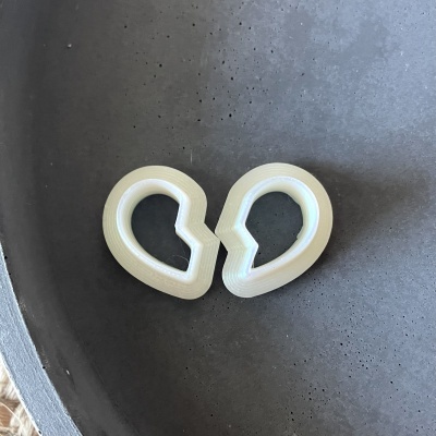 Dois acessórios de plástico branco sobre superfície cinza pontilhada