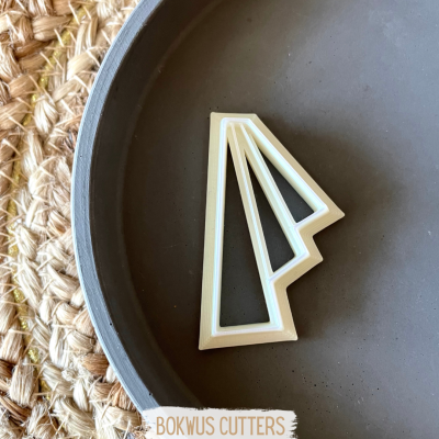 cortador de massa branco com design geométrico num prato cinzento