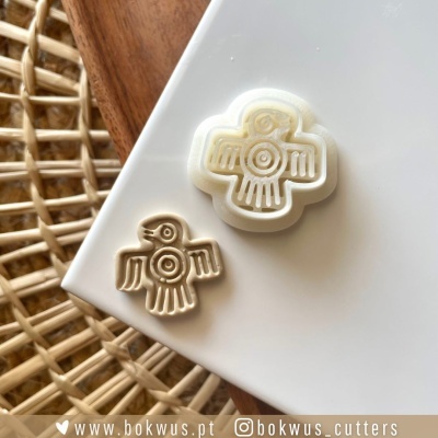 Dois cortadores de biscoito em forma de pássaro sobre superfície branca e madeira com fundo de cesto