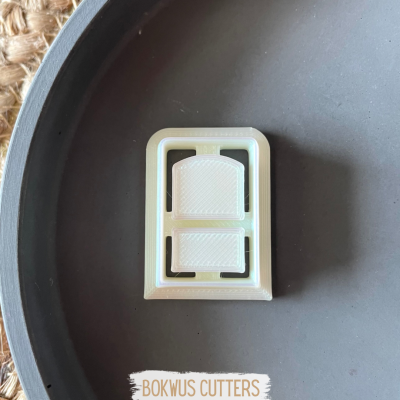 Cortador de bolachas branco retangular com duas partes internas em superfície cinza escuro