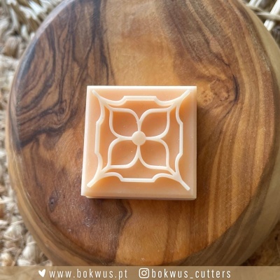 Cortante quadrado de plástico com padrão floral em relevo sobre base de madeira