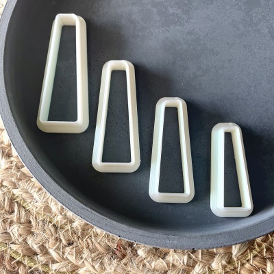 Quatro moldes trapezoidais claros numa bandeja cinzenta sobre superfície de fibra natural.