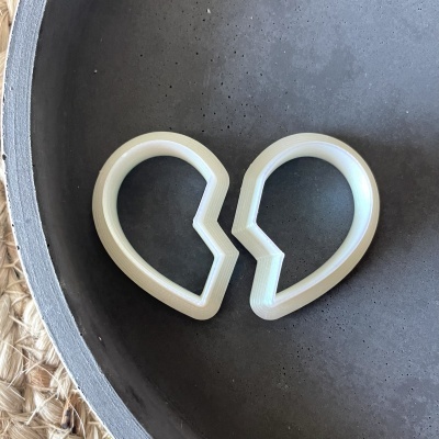 Dois cortadores de biscoitos em forma de coração partido em tabuleiro cinza.