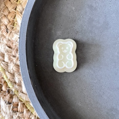 anel ursinho translúcido em prato cinza sobre tapete de fibras naturais