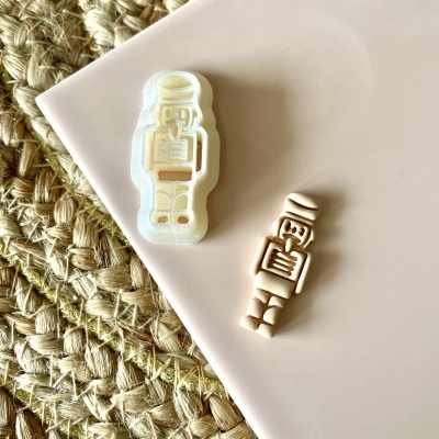 Carimbo composto por duas partes formando a figura de um astronauta em superfície branca com tapete de fibras ao fundo