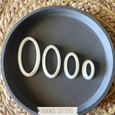 Conjunto de cortadores ovais brancos em forma preta sobre superfície trançada