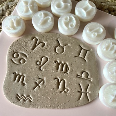 Selos de plástico com símbolos do zodíaco e placa de argila com sinais gravados