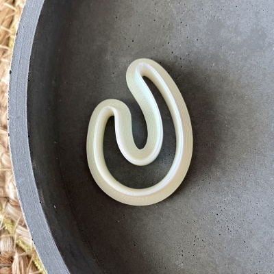 Objeto ondulado creme num prato cinzento com fundo de fibra natural