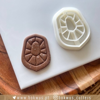 Molde ou cortador em plástico branco e massa castanha com textura irregular