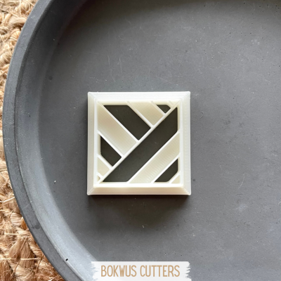 Cortante geométrico branco sobre prato cinza com texto BOKWUS CUTTERS