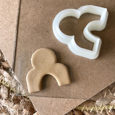 Cortador de bolachas branco e bolacha modelada na mesma forma em superfície de cartão castanho