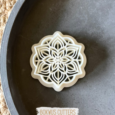 Cortador de biscoitos branco em formato de mandala num prato escuro com texto BOKWUS CUTTERS