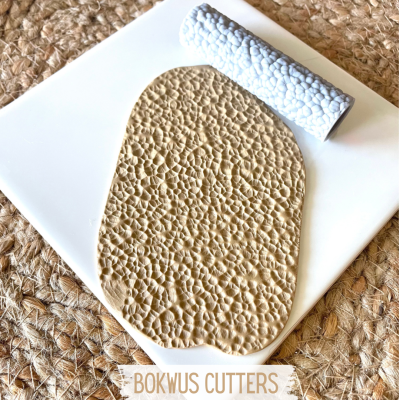 massa de modelar bege texturizada com rolo branco texturizador sobre base branca