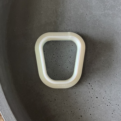 Peça moldada em plástico bege claro sobre superfície cinza porosa