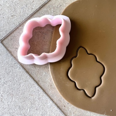 Cortador de biscoito rosa e massa castanha com formato ondulado