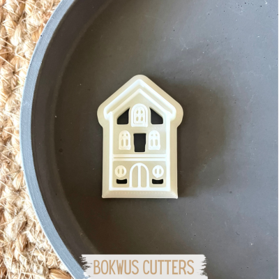 Cortante branco em forma de casa sobre prato cinzento