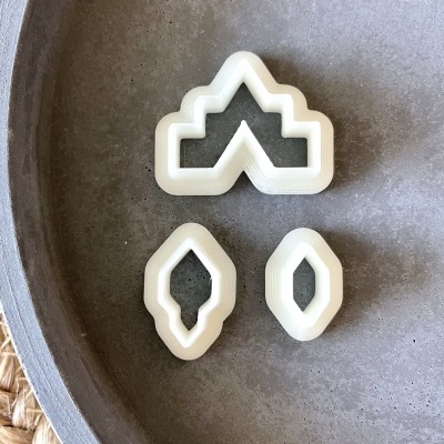 Cortadores de massa plásticos brancos em formas geométricas sobre prato cinza