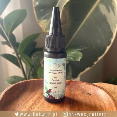 Frasco de resina UV curável com rótulo floral em prato de madeira e plantas ao fundo