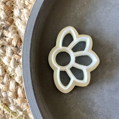 Forma branca de plástico em forma de flor sobre prato cinzento