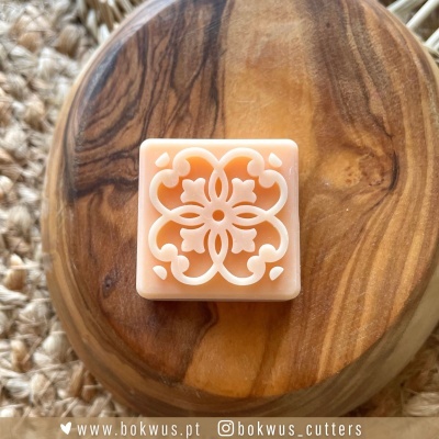 Cortador de biscoitos quadrado com padrão floral sobre tábua de madeira